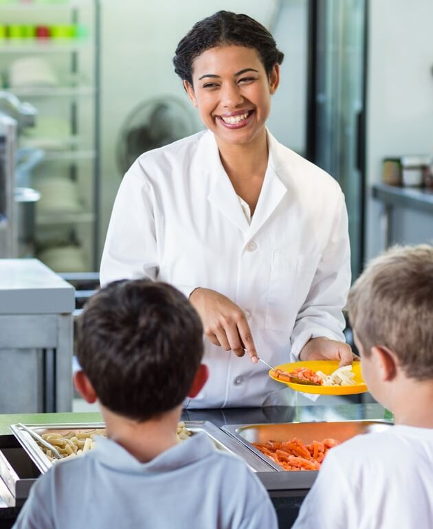 Cafeteria lady serving children in line at school