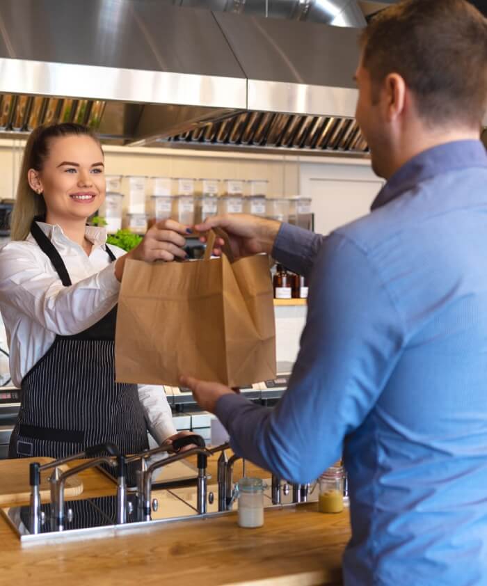 Man picking up order at restaurant from friendly staff.